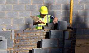 A worker lays bricks for a residential home at a building site in north London